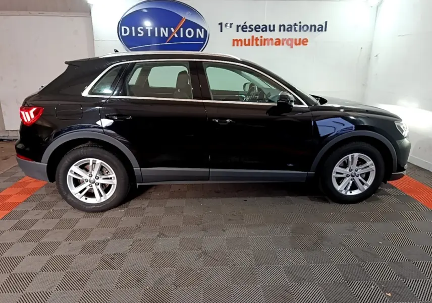 Profil côté gauche d'un Audi Q3 noir 2020 garé en intérieur avec jantes argentées et feux arrière allumés.