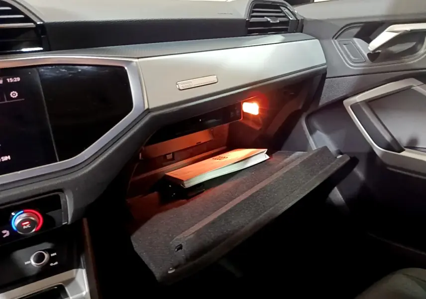 Vue intérieure côté passager de l'Audi Q3 35 TDI 150 S tronic Business Line 2020, boîte à gants ouverte avec manuel visible.