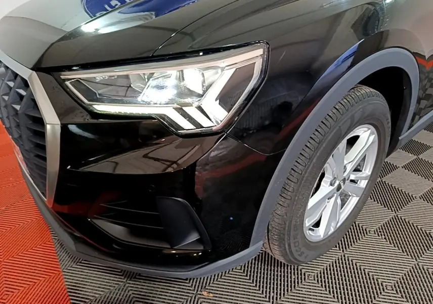 Gros plan sur l'avant droit noir d'un Audi Q3 35 TDI 150 S tronic avec phare LED et jante argentée.