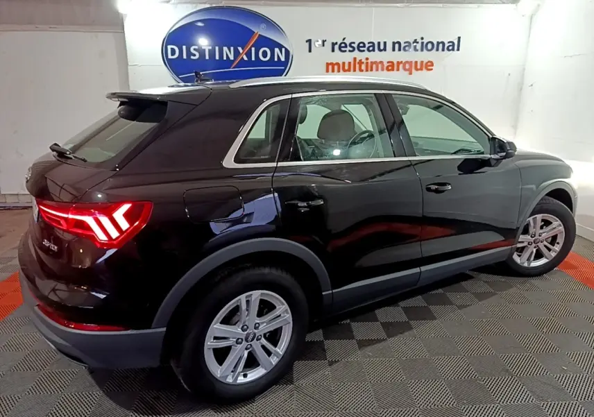 Audi Q3 35 TDI noir vue de profil côté droit en intérieur avec feux arrière allumés et jantes argentées.