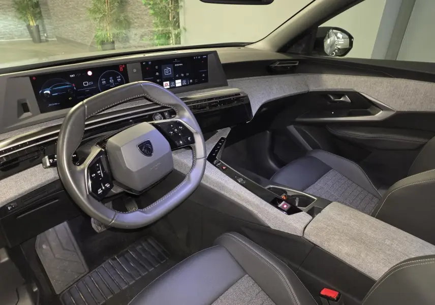 Intérieur avant droit du Peugeot 3008 2025 hybride, avec tableau de bord numérique et sellerie tissu gris chiné.