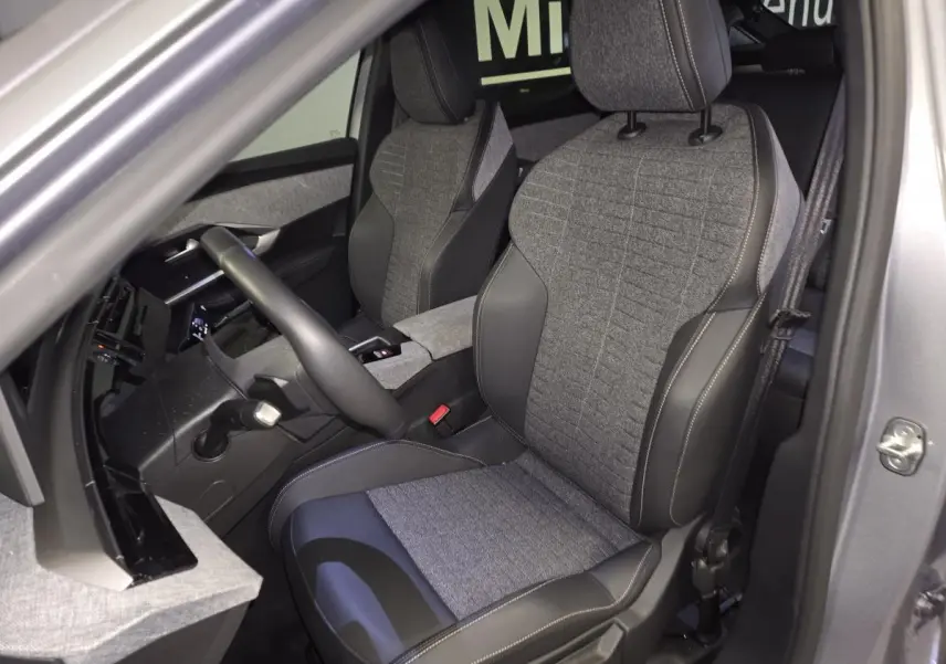 Vue intérieure côté conducteur du Peugeot 3008 gris 2025, sièges tissu gris et cuir noir avec surpiqûres quartz.