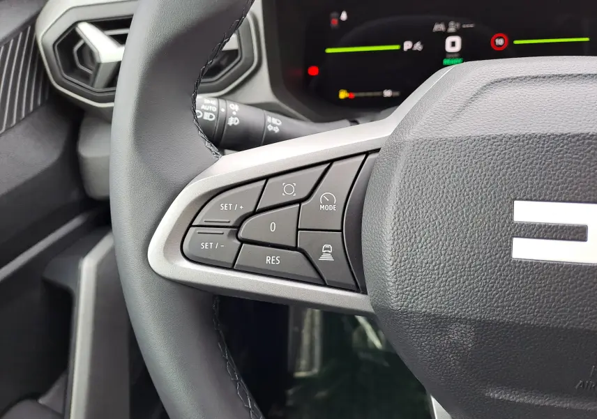 Gros plan sur la partie gauche du volant du Dacia Bigster 2026, avec commandes de régulateur et tableau de bord numérique en arrière-plan.