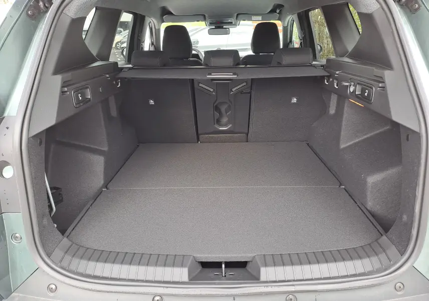 Coffre ouvert vu de l'arrière du Dacia Bigster vert cèdre, montrant un espace de chargement plat et bien aménagé.