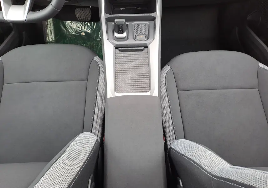 Vue intérieure centrée sur la console et les sièges avant gris du Dacia Bigster Hybrid 155 Journey, détails modernes visibles.