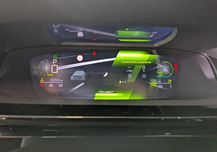 Affichage numérique du tableau de bord de la Peugeot 408 Hybrid 145 GT, montrant la consommation instantanée et l'autonomie.