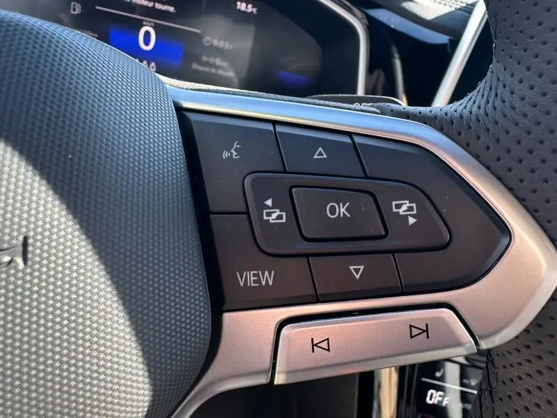 Gros plan sur les commandes multifonctions noires et argentées du volant perforé du Volkswagen T-Roc noir intense nacré.