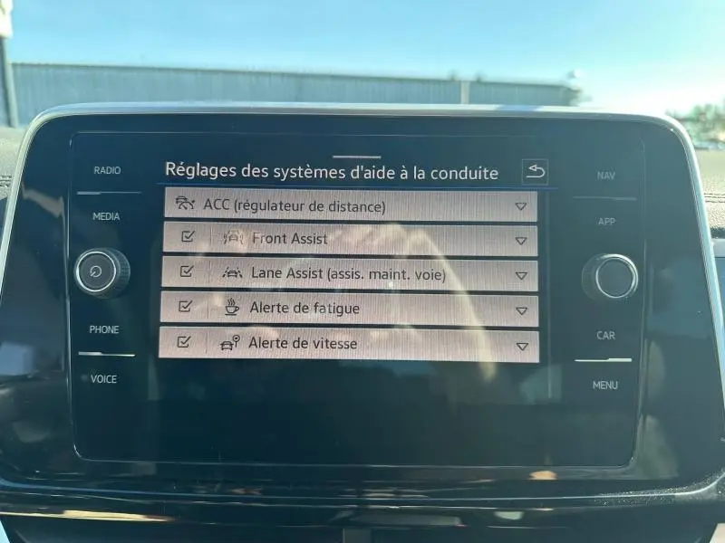 Écran tactile central du Volkswagen T-Roc 2025 affichant les réglages des aides à la conduite, intérieur noir.