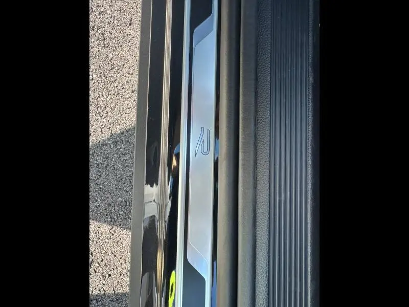 Gros plan sur la plaque de seuil de porte noire nacrée du Volkswagen T-Roc 1.5 TSI Evo2 R-Line avec logo R distinctif.