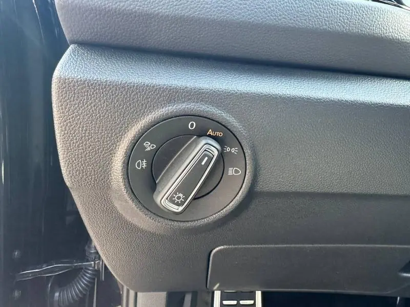 Gros plan sur le bouton de commande des phares noir dans l'habitacle du Volkswagen T-Roc 2025 noir nacré.