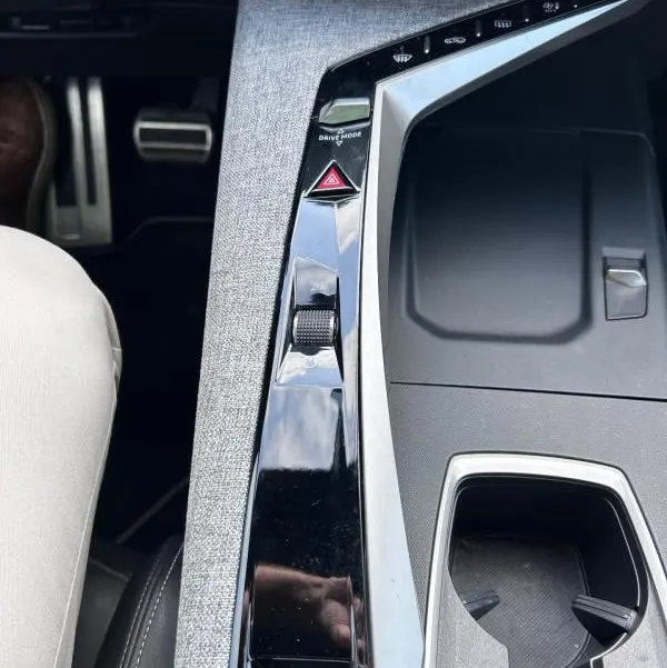 Vue rapprochée de la console centrale grise du Peugeot 3008 Hybrid 136 e-DCS6 GT avec commandes Drive Mode et bouton de warning.