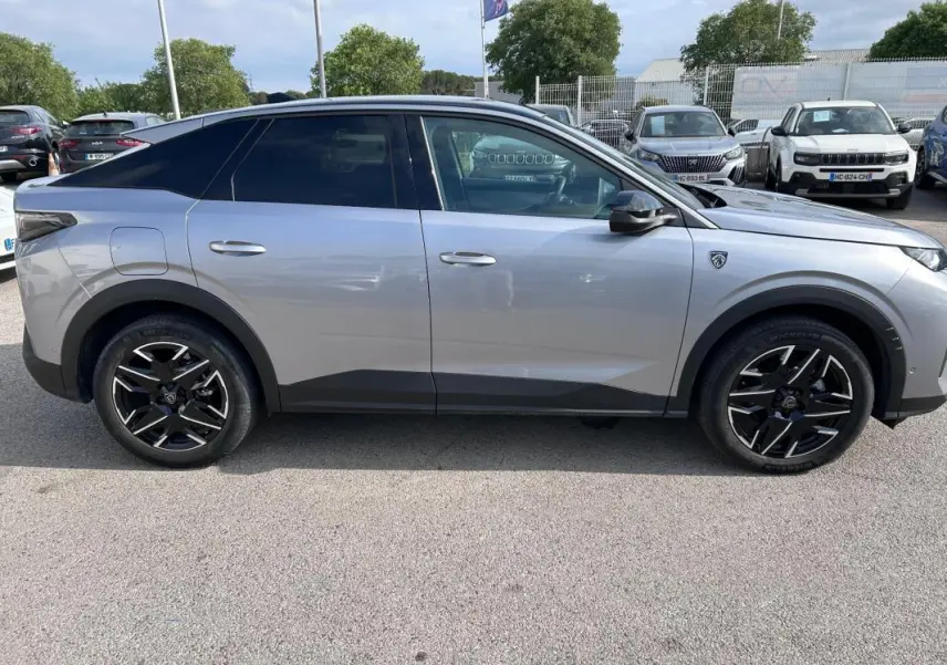 Vue de profil côté gauche d’un Peugeot 3008 Hybrid gris clair avec jantes alliage noires 19 pouces et toit ouvrant.