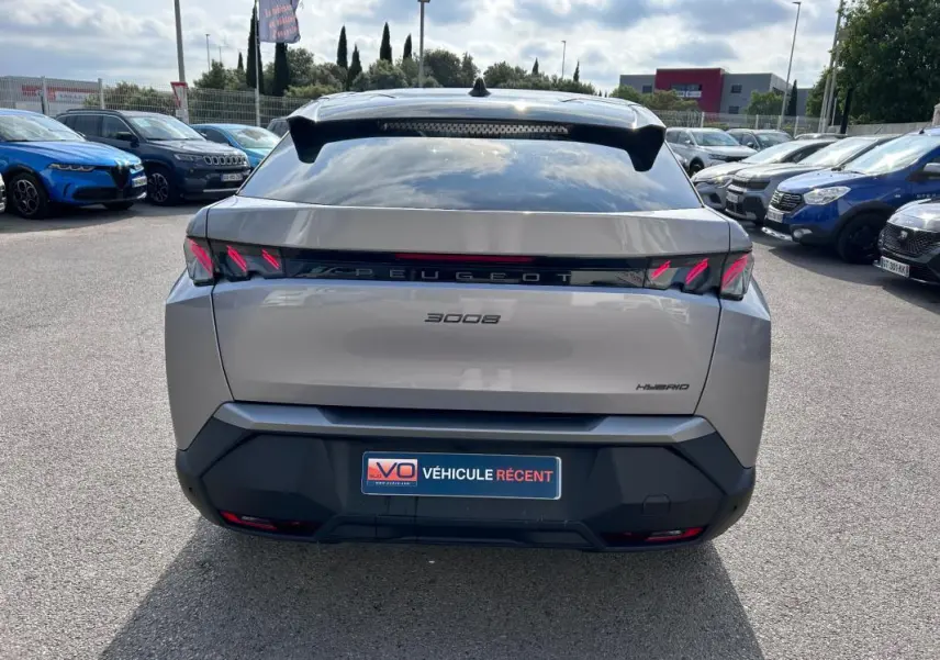 Vue arrière d’un Peugeot 3008 Hybrid gris clair 2025 avec feux LED distinctifs et toit ouvrant visible.