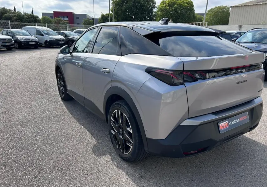Vue 3/4 arrière droite d’un Peugeot 3008 Hybrid gris clair avec jantes alliage 19 pouces et toit ouvrant noir.