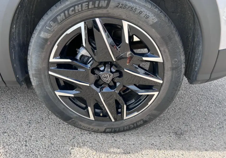 Gros plan sur la jante alliage noire et argent de 19 pouces du Peugeot 3008 Hybrid gris clair, roue avant droite.