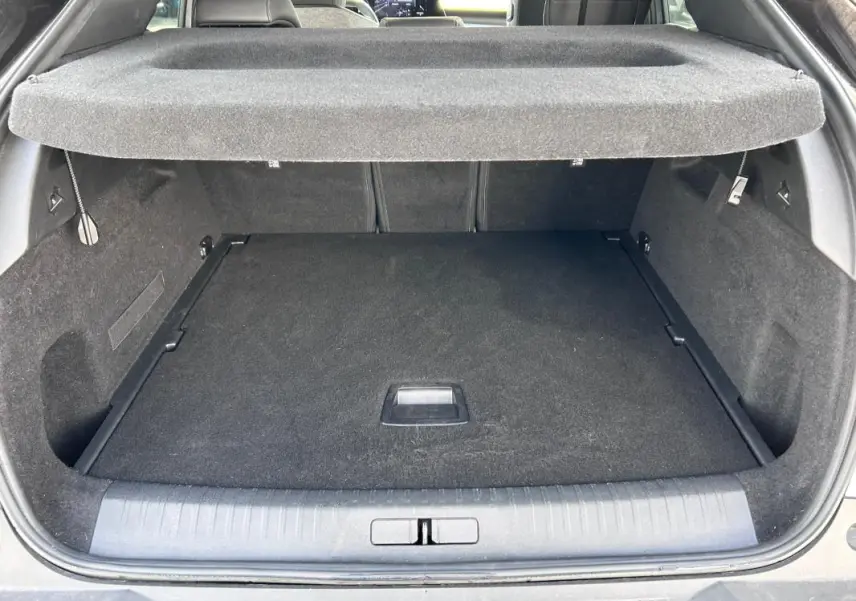 Coffre ouvert vu de l'arrière du Peugeot 3008 gris clair, montrant un espace de chargement propre et couvert.
