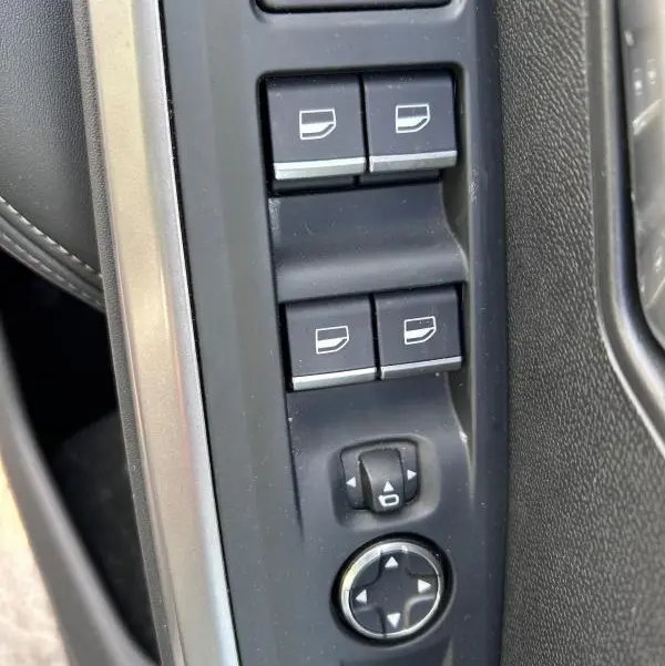 Vue rapprochée des commandes de lève-vitres et réglages des rétroviseurs côté conducteur du Peugeot 3008 Hybrid gris clair 2025.