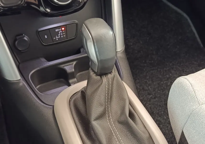 Le levier de vitesse automatique noir avec soufflet cuir beige clair, console centrale et siège tissu clair partiel visible.