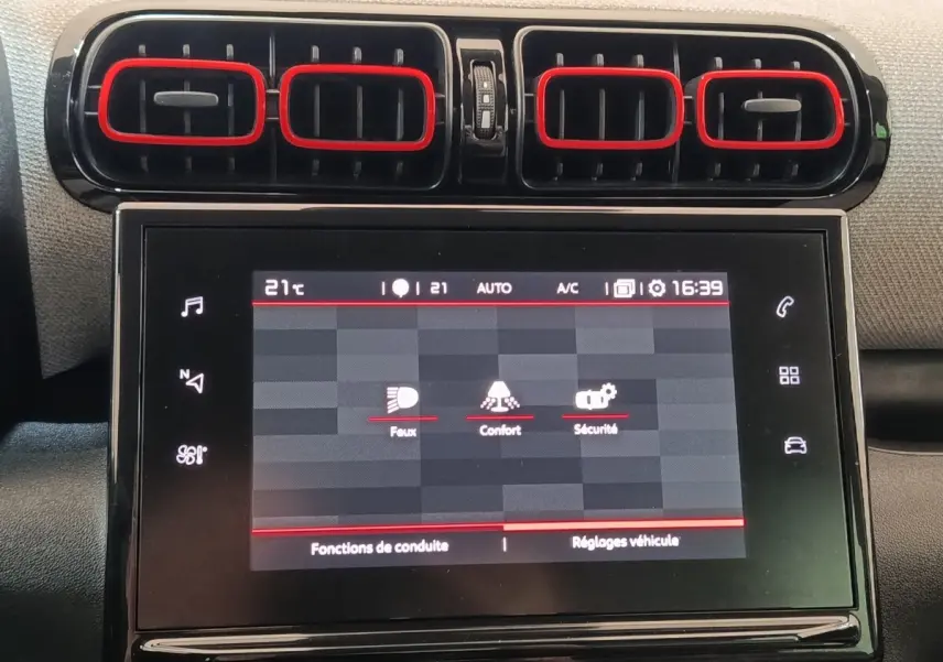 Écran tactile central et aérateurs rectangulaires noirs avec contours rouges dans le tableau de bord d'une Citroën C3 Aircross beige.