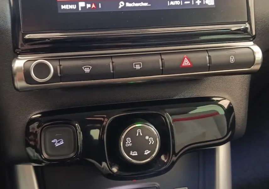 Gros plan sur la console centrale noire du Citroën C3 Aircross beige, avec commandes de traction et boutons de sécurité.