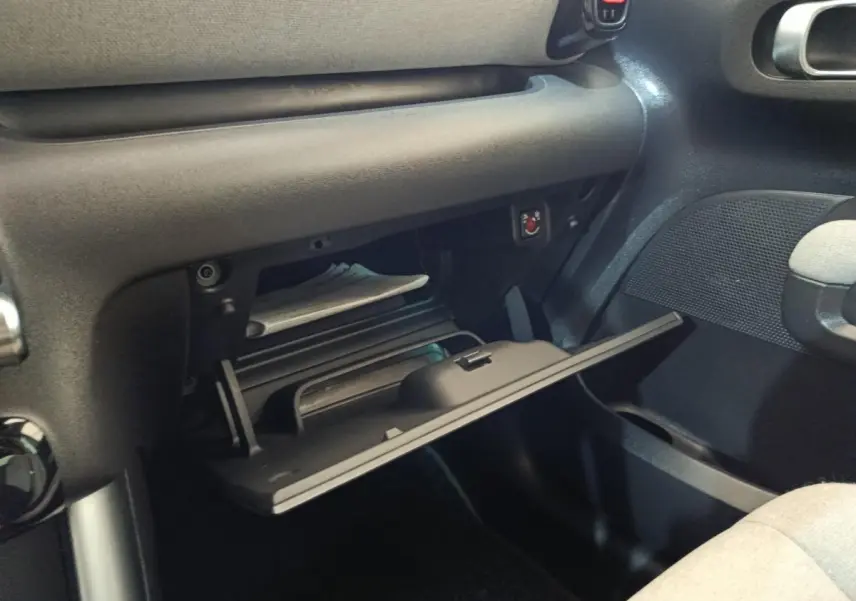 Vue intérieure côté passager du coffre à gants ouvert de la Citroën C3 Aircross beige, montrant son rangement et la texture du tableau de bord.