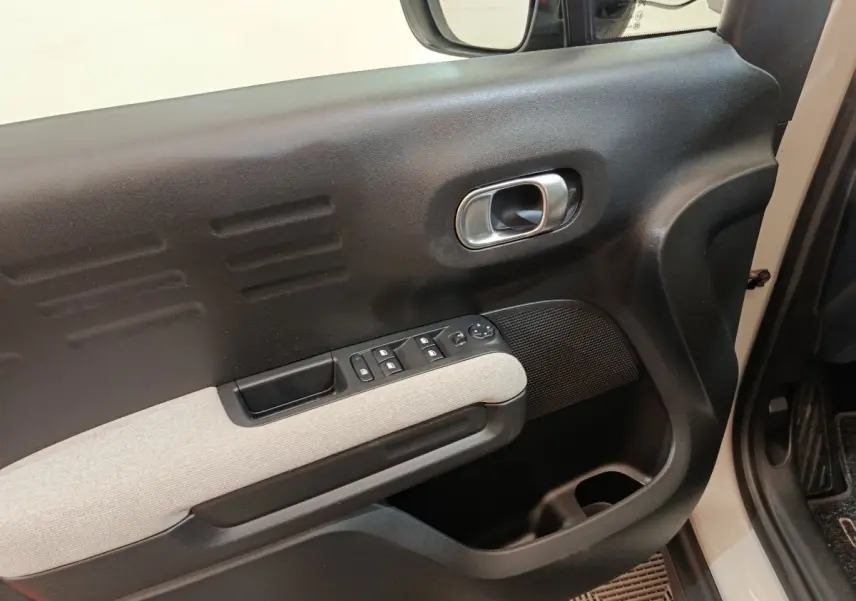 Vue rapprochée de la porte avant gauche beige du Citroën C3 Aircross avec commandes de vitres et poignée argentée.