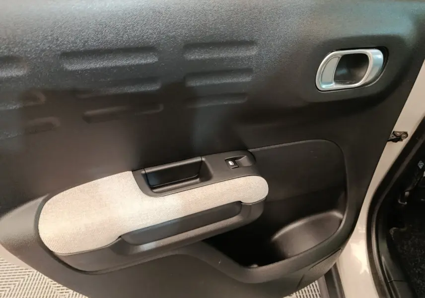 Détail de la porte avant droite beige et noire de la Citroën C3 Aircross 2021 avec poignée intégrée et bouton de vitre électrique.