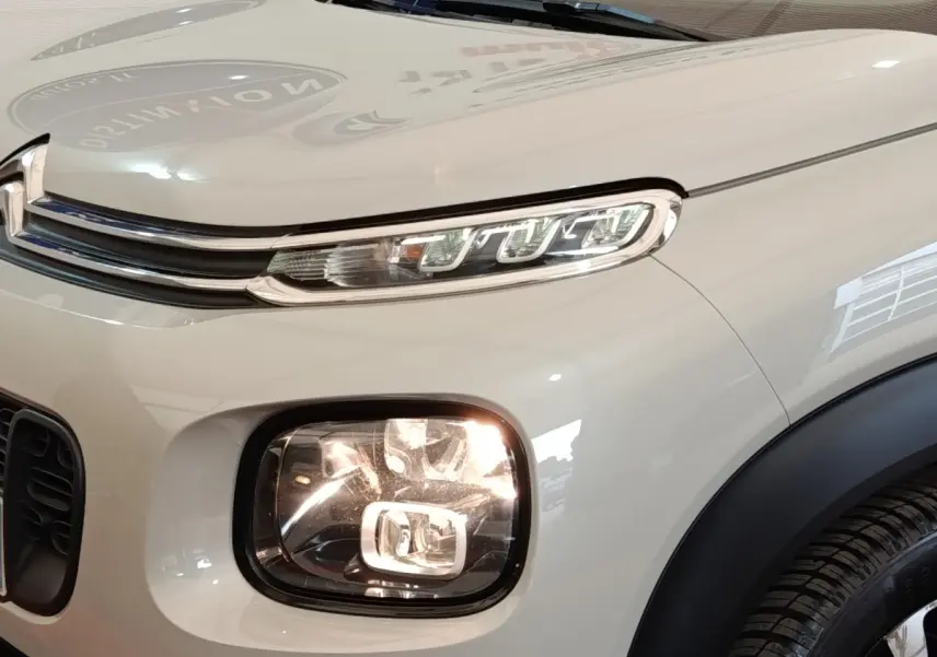 Gros plan sur l'avant droit beige du Citroën C3 Aircross avec ses phares LED distinctifs et la calandre chromée.