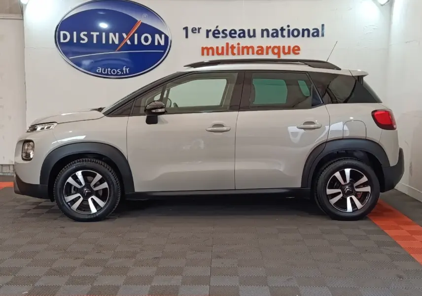 Vue de profil côté gauche d'un Citroën C3 Aircross beige 2021 avec toit noir et jantes bicolores.