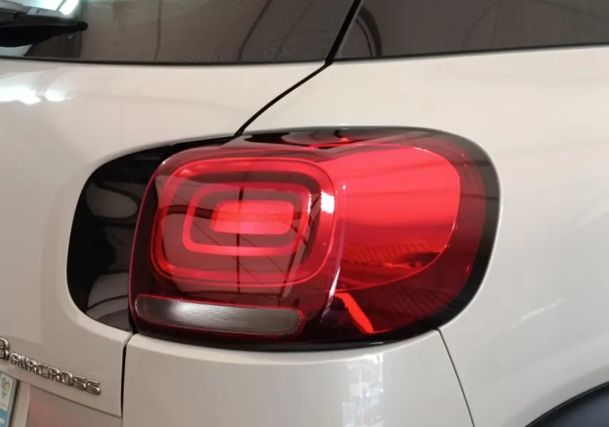 Gros plan sur le feu arrière droit rouge et la carrosserie beige d'une Citroën C3 Aircross 2021.