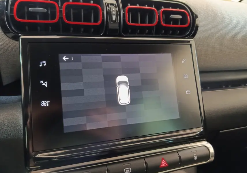 Vue rapprochée de l’écran tactile central et des aérateurs noirs avec contours rouges dans l’habitacle du Citroën C3 Aircross beige.