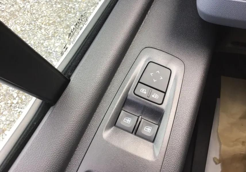 Gros plan sur les commandes électriques des vitres et des rétroviseurs côté conducteur d’un Renault Master blanc 2026.