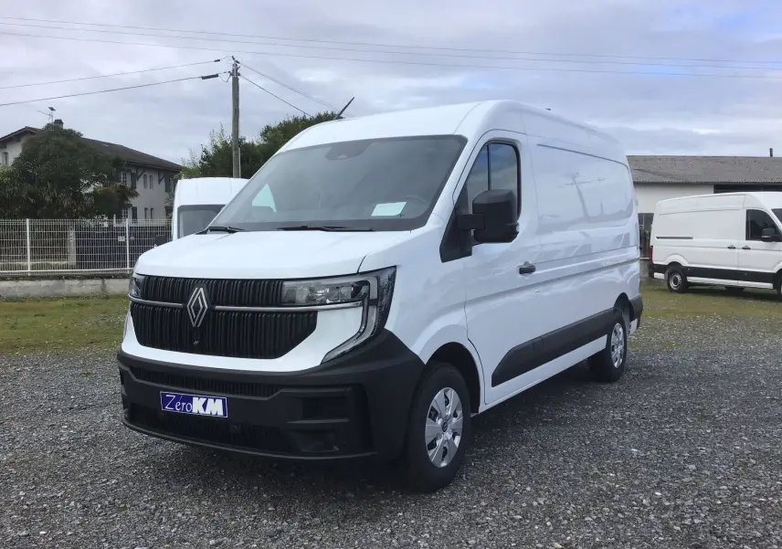 Renault Master blanc en vue 3/4 avant droit, avec calandre noire et pare-chocs avant noir mat sur terrain gravillonné.