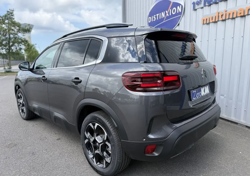 Vue 3/4 arrière droite du Citroën C5 Aircross gris platinium métal, avec jantes noires et vitres teintées.