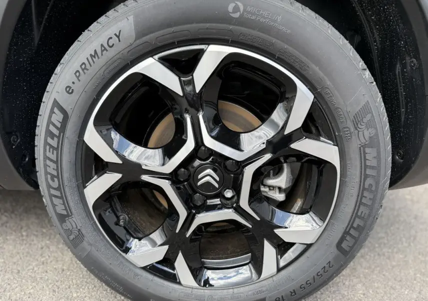 Gros plan sur la jante noire et argentée du Citroën C5 Aircross gris platinium, mettant en valeur le logo Citroën central.