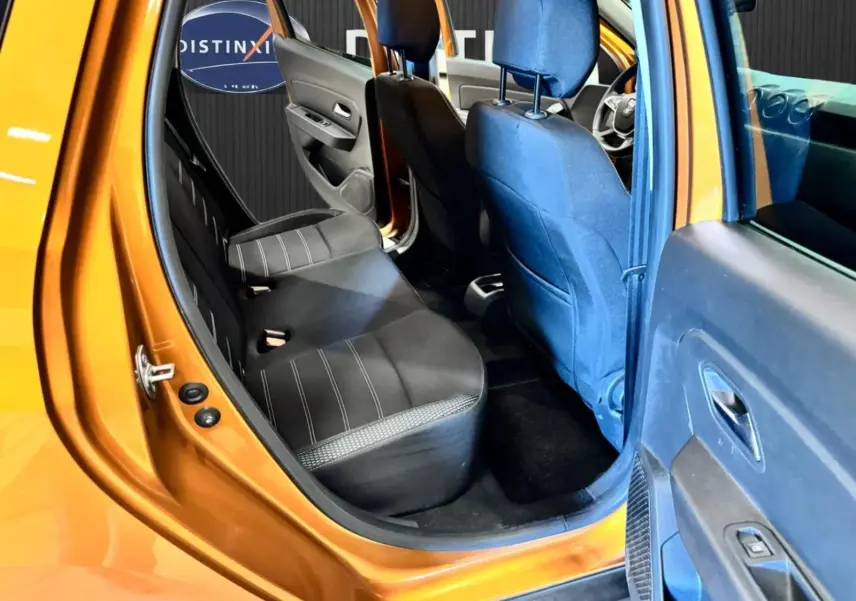 Vue intérieure côté gauche arrière du Dacia Duster orange 2020, montrant les sièges noirs et la porte ouverte.