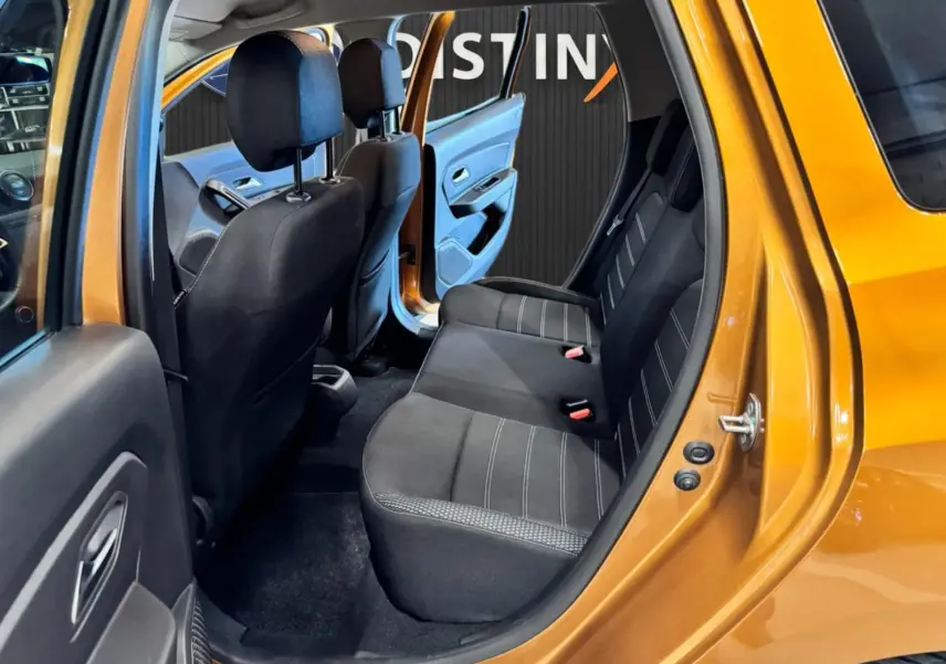 Vue intérieure côté gauche arrière du Dacia Duster orange 2020, montrant les sièges arrière en tissu noir avec surpiqûres grises.