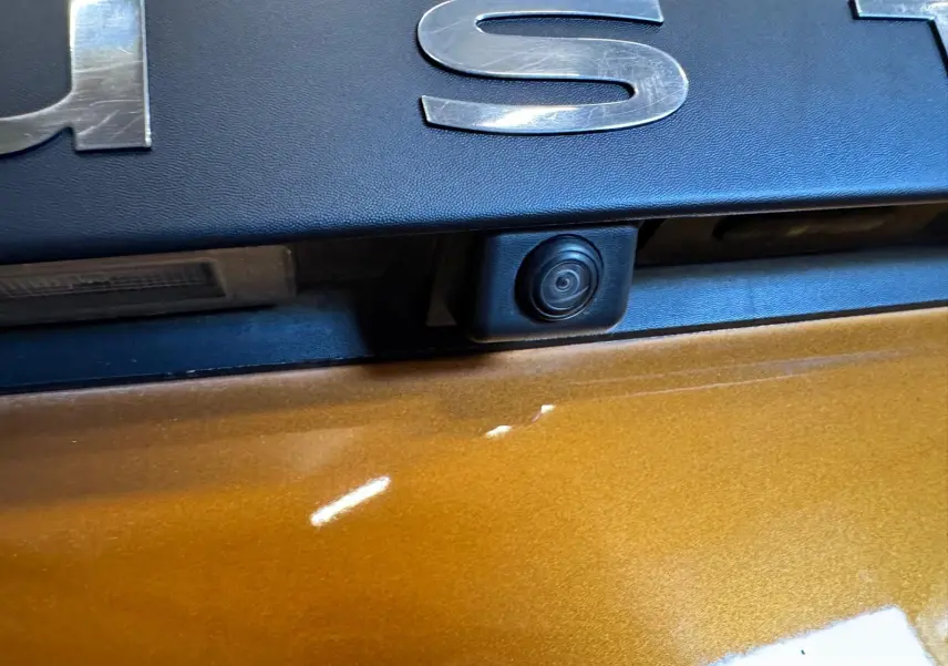 Gros plan sur la caméra de recul intégrée sous le logo Dacia sur la porte arrière orange du Duster 2020.