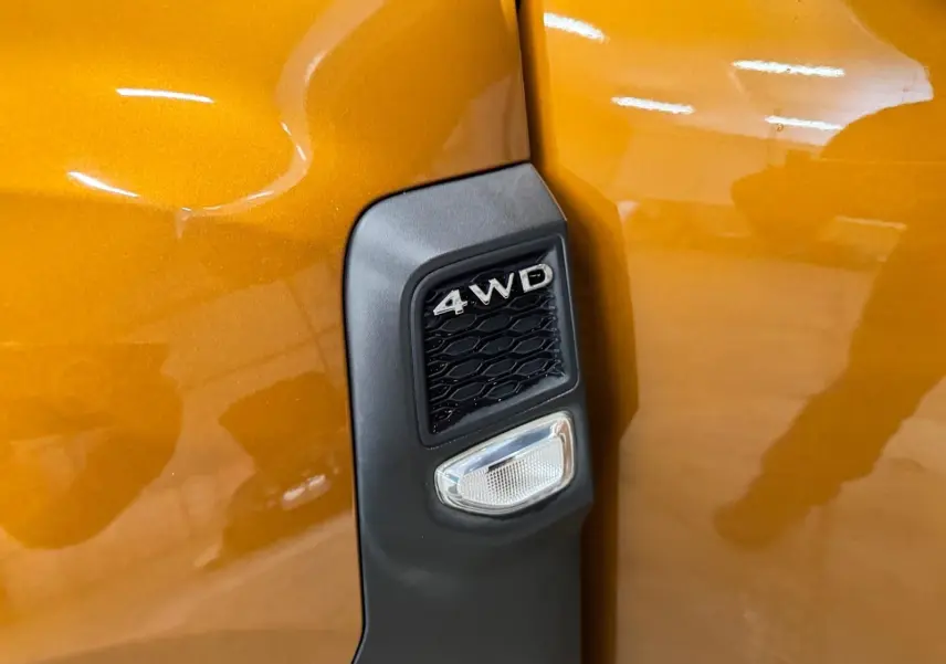 Détail de l'aile avant droite orange du Dacia Duster 2020 avec badge 4WD noir et clignotant intégré.