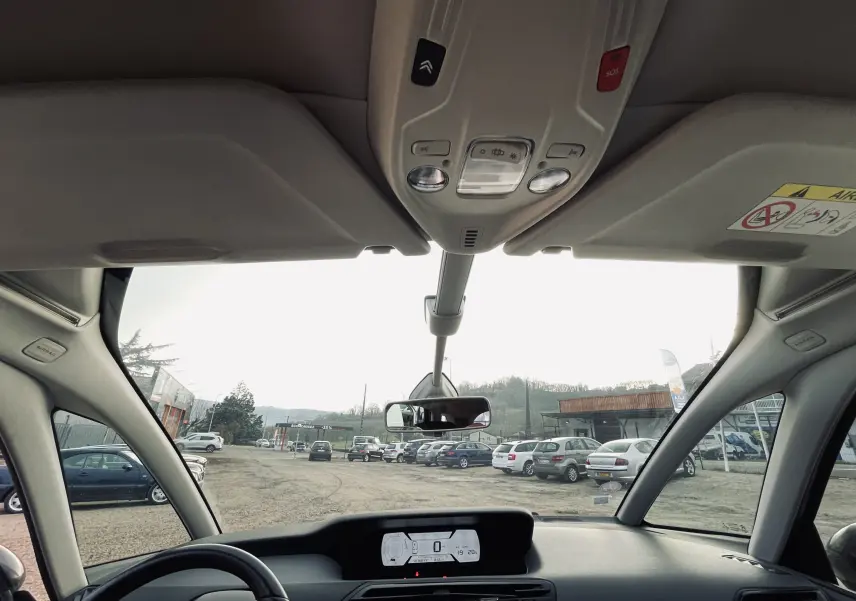 Vue intérieure avant du tableau de bord et du pare-brise panoramique d'une Citroën C4 Picasso gris clair.