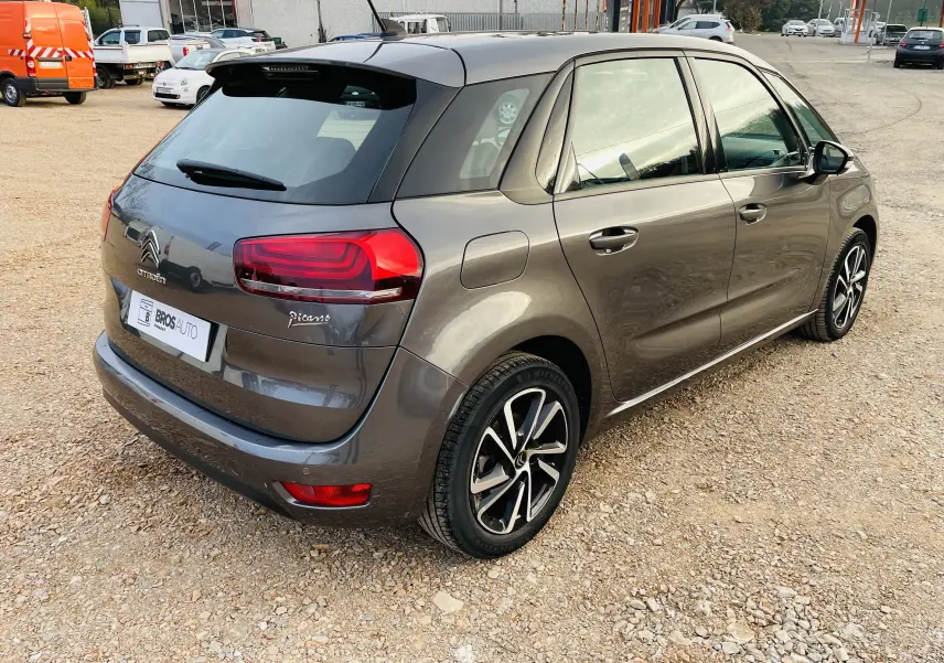 Vue 3/4 arrière droite d'une Citroën C4 Picasso II grise métal avec feux arrière LED et jantes alliage noires.