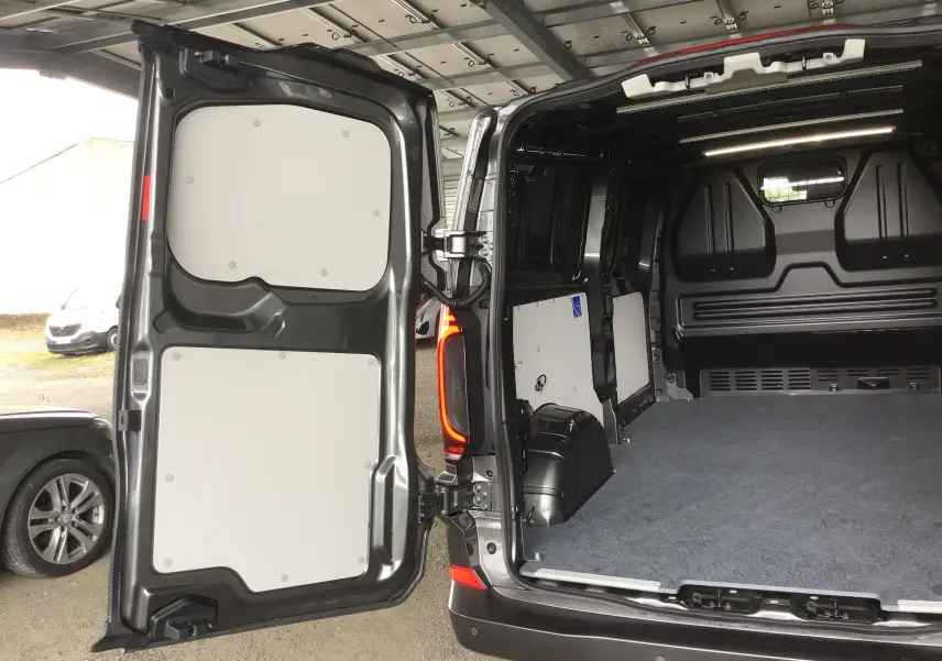 Vue arrière ouverte du Volkswagen Transporter T7 gris anthracite montrant l'espace de chargement vide et les portes battantes.