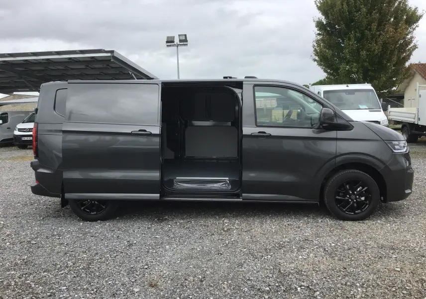 Vue latérale gauche du Volkswagen Transporter T7 gris anthracite avec porte coulissante ouverte révélant l'espace de chargement.