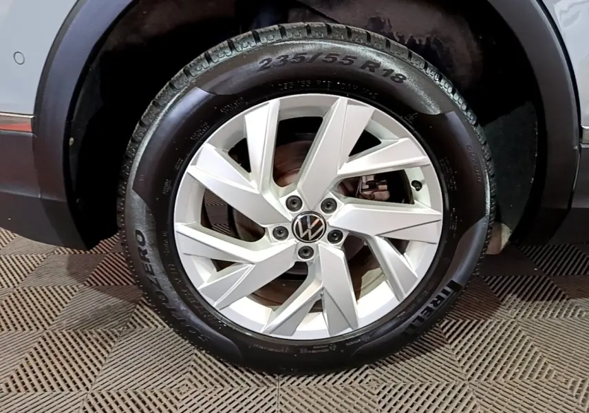 Gros plan sur la roue avant droite du Volkswagen Tiguan gris foncé avec jante alliage à design moderne.