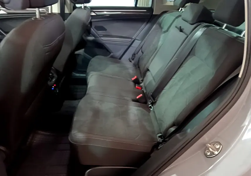 Vue latérale intérieure des sièges arrière gris foncé du Volkswagen Tiguan 2021, montrant les ceintures et appuie-têtes.