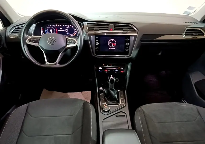 Vue intérieure avant du Volkswagen Tiguan 2.0 TDI 2021, tableau de bord noir avec écran tactile et volant cuir multifonctions.
