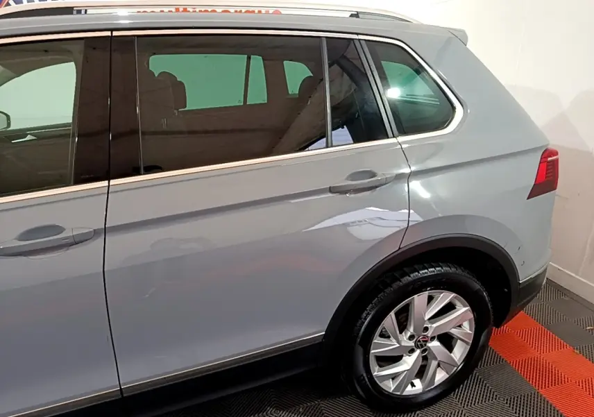 Vue latérale côté droit d'un Volkswagen Tiguan gris foncé avec jantes alliage et vitres teintées.