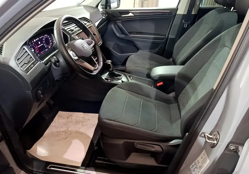 Intérieur du Volkswagen Tiguan 2021 vu côté conducteur, sièges gris foncé et tableau de bord digital lumineux.