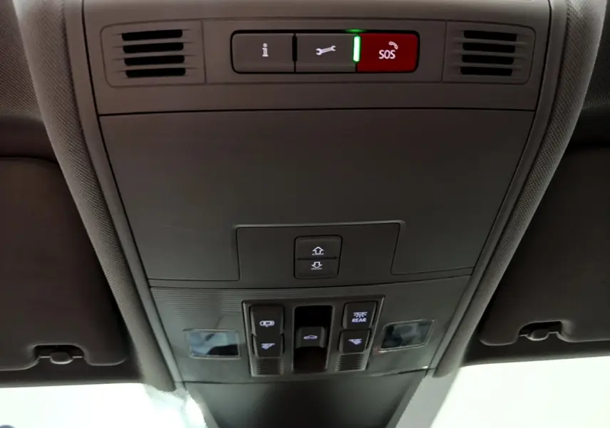 Vue en contre-plongée du panneau de commandes au plafond gris foncé du Volkswagen Tiguan 2021 avec bouton SOS rouge allumé.