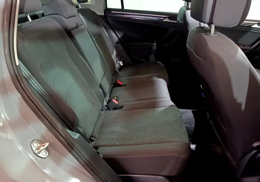 Vue intérieure côté gauche des sièges arrière gris foncé du Volkswagen Tiguan 2021 avec garniture tissu et ceintures visibles.